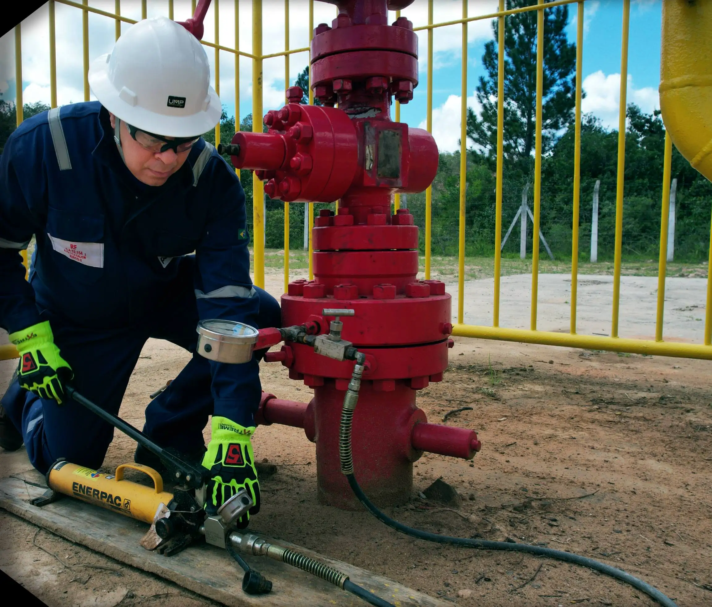 Operador com capacete de segurança próximo a uma válvula industrial vermelha